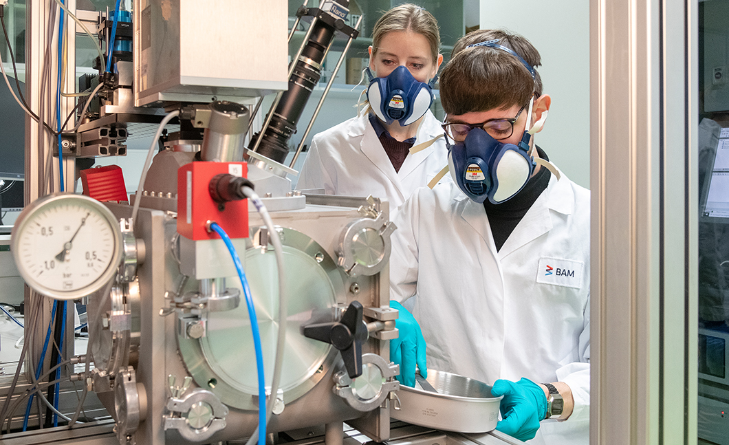 Philipp Breese and Tina Becker fill the 3D printer with metallic powder.