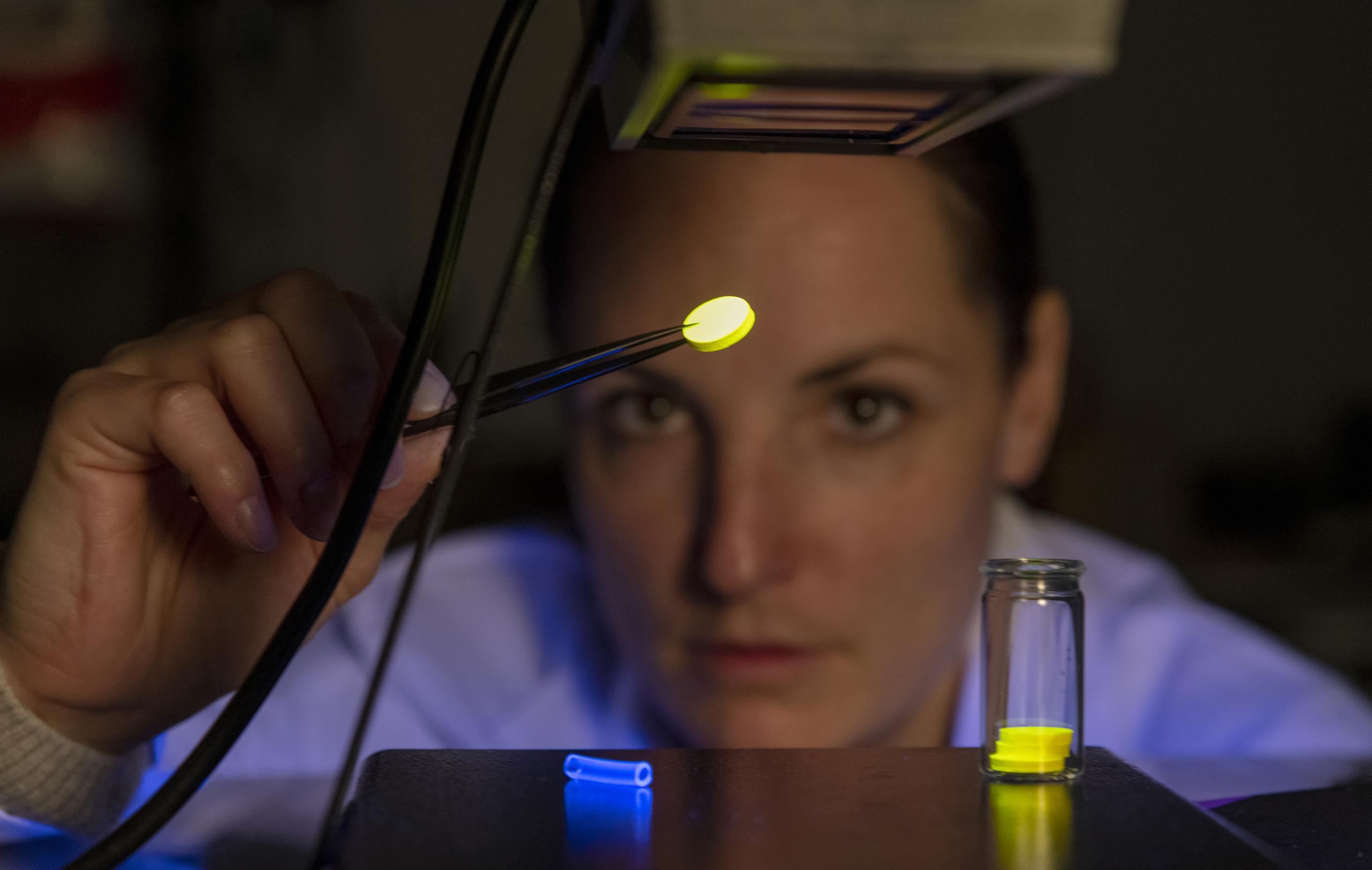 Eine Frau untersucht Materialien unter fluoreszierendem Licht. Eine Frau untersucht Materialien unter fluoreszierendem Licht.
