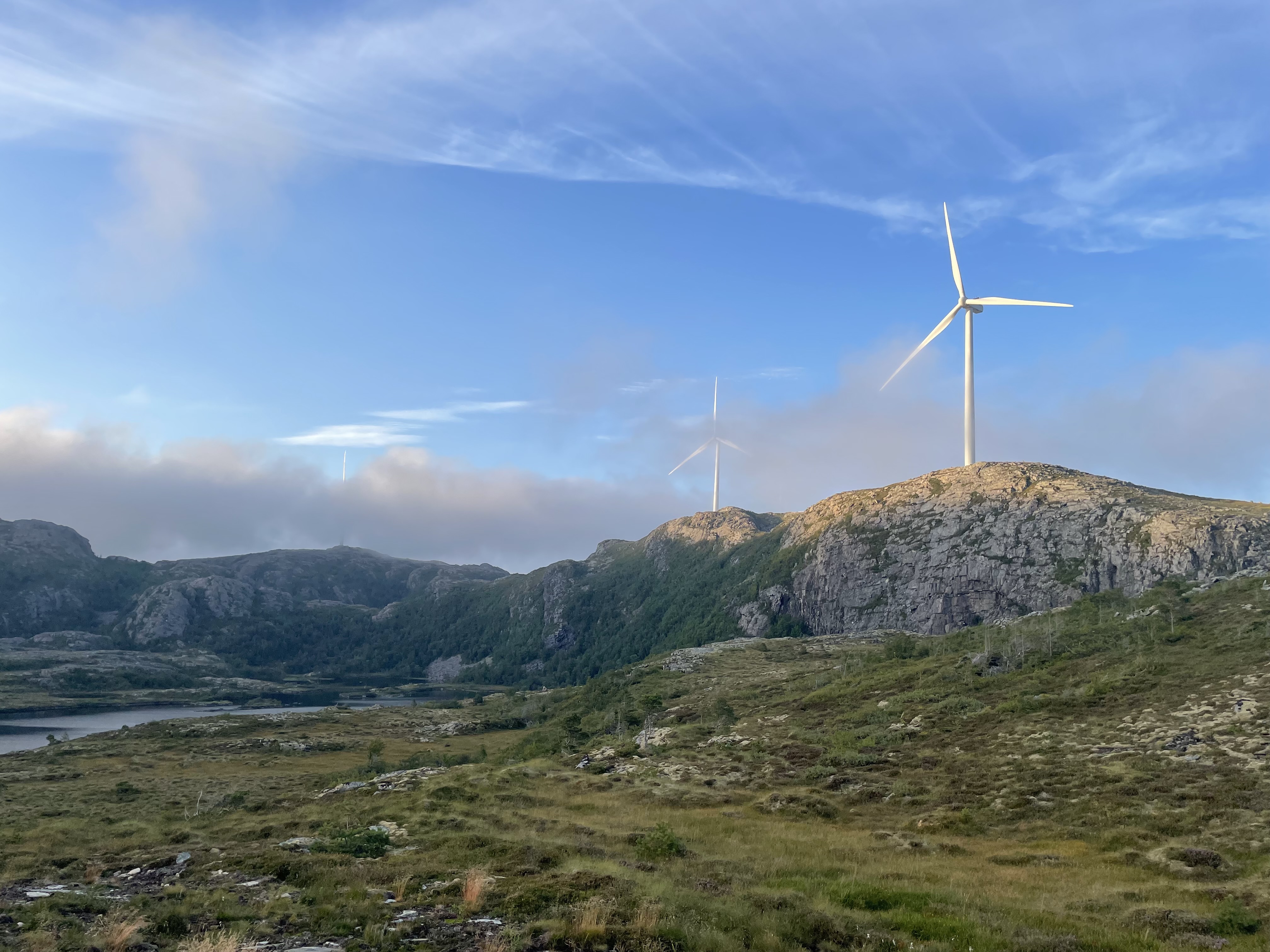 Zwei Windräder auf felsigen Bergen vor blauem Himmel und Wolken. Zwei Windräder auf felsigen Bergen vor blauem Himmel und Wolken.