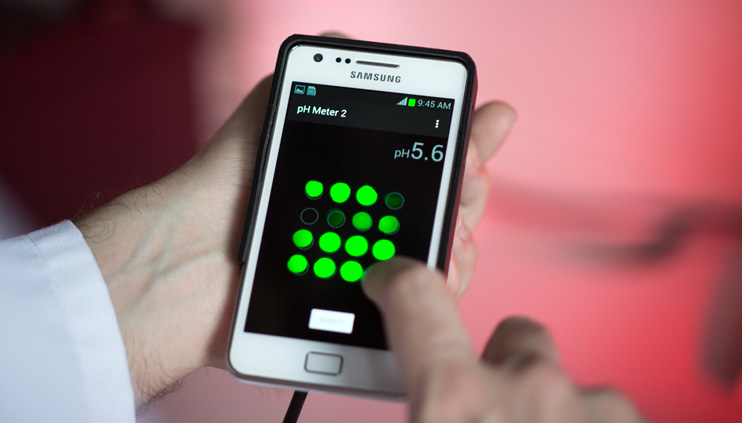 Ein BAM-Mitarbeiter hält ein Smartphone mit einem PH-Schnelltest in der Hand.