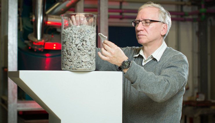 BAM-Mitarbeiter mit einem Behälter, gefüllt mit Asche aus verbranntem Hausmüll.