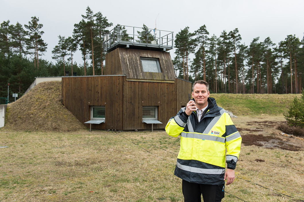 Dr. Kai Holtappesl in front of the observation bunker on the BAM Test Site at Horstwalde: he is in touch by mobile with colleagues who are preparing a steel container for a test series on the explosion stand.