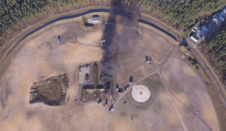 A bird's eye view of a fire test with a plume of smoke that is visible from a distance.