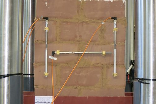 Earth block masonry elements during compressive strength testing in the testing machine with measuring sensors Earth block masonry elements during compressive strength testing in the testing machine with measuring sensors