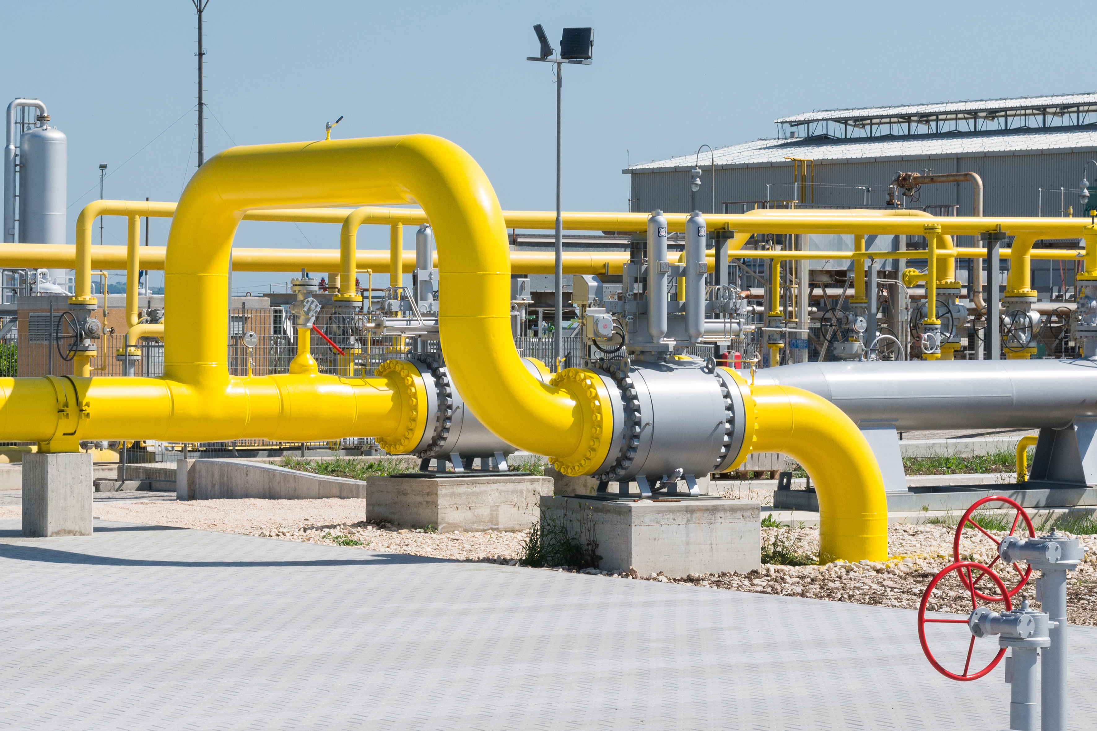 A yellow pipe running overground across a factory yard. A yellow pipe running overground across a factory yard.