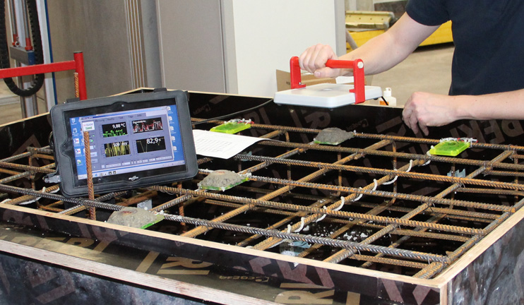 A BAM employee holds a reader device over sensors that are built into a steel grid for a concrete casing. A BAM employee holds a reader device over sensors that are built into a steel grid for a concrete casing.