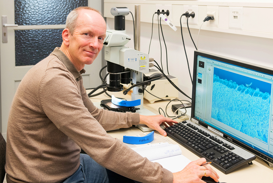 Dr. Dirk Bettge with a material sample under an optical microscope.