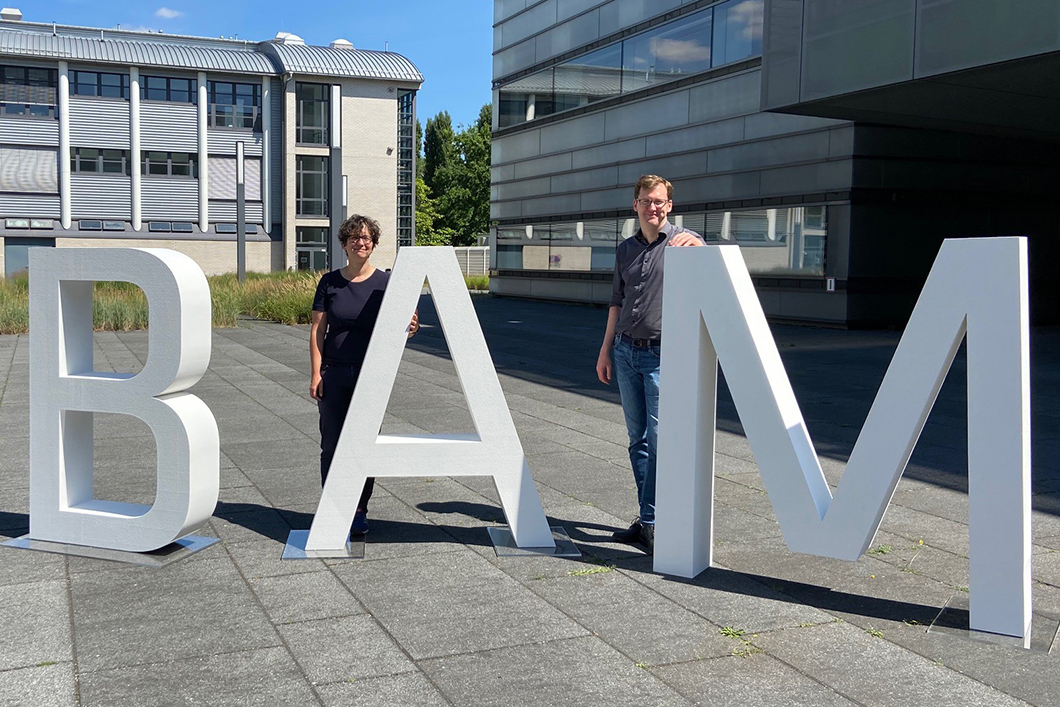 SFB Fluor-Spezifische Wechselwirkungen Dr. Franziska Emmerling und Dr. Björn Meermann vor den BAM-Buchstaben in Adlershof
