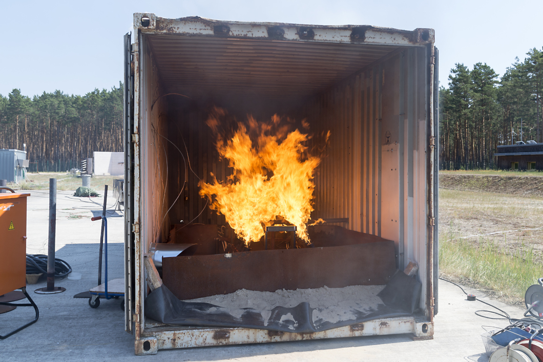 Brandcontainer Ein Container in freiem Gelände, in dem ein Feuer brennt.