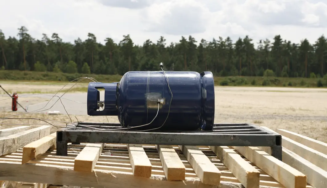 Unterfeuerungsversuch mit 11 kg Propangasflasche Eine 11 kg Propangasflasche, vorbereitet für einen Unterfeuerungsversuch mit Holz.