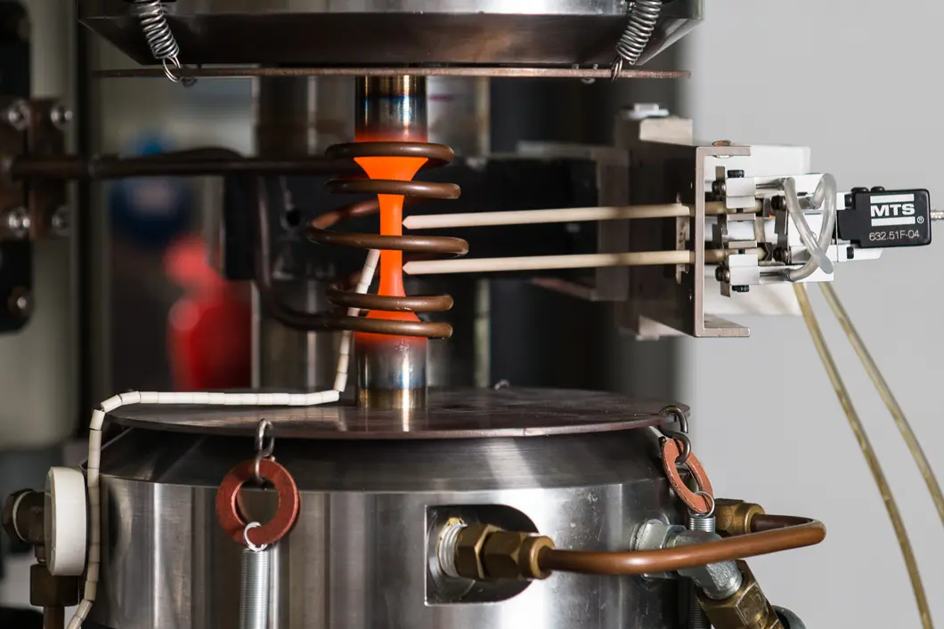 The transition quartet This is what the experimental set-up looks like in detail: the column-shaped steel sample is clamped solidly and exposed to compression and tension. Sensors measure the resulting changes in the metal.